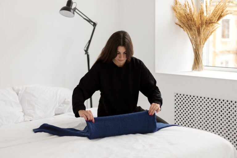 an airbnb host folding blankets in an airbnb